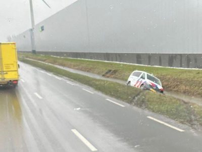Politieauto schiet van de weg en belandt in sloot